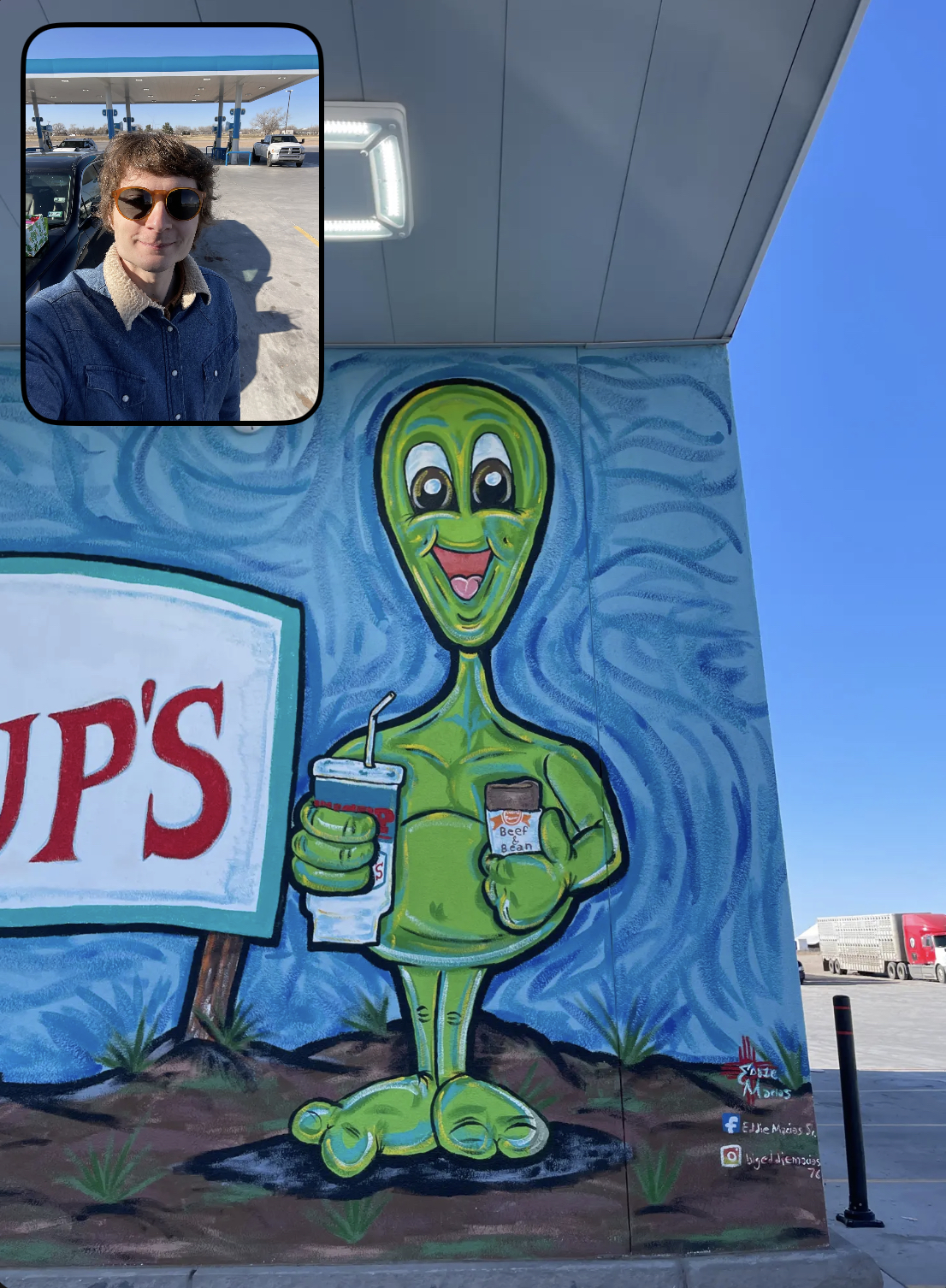 A mural of a cartoonish green alien on the side of a gas station near Roswell, New Mexico, with a selfie of me superimposed on the corner of the image.
