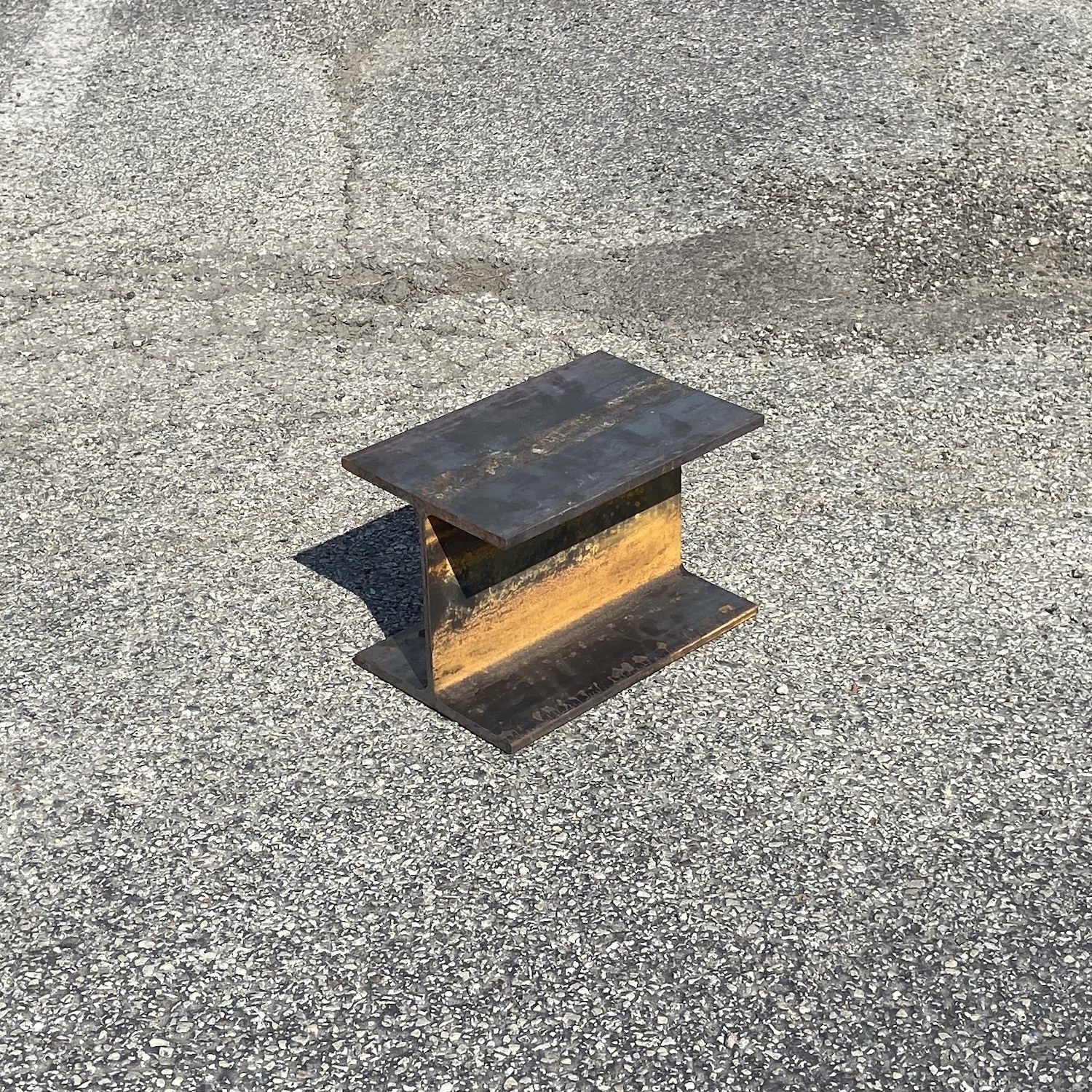 An anvil made out of steel I-beam, photographed in a parking lot.