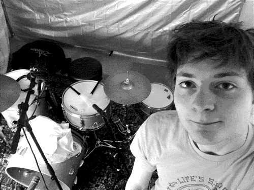 An animated selfie of Spencer at a drum set